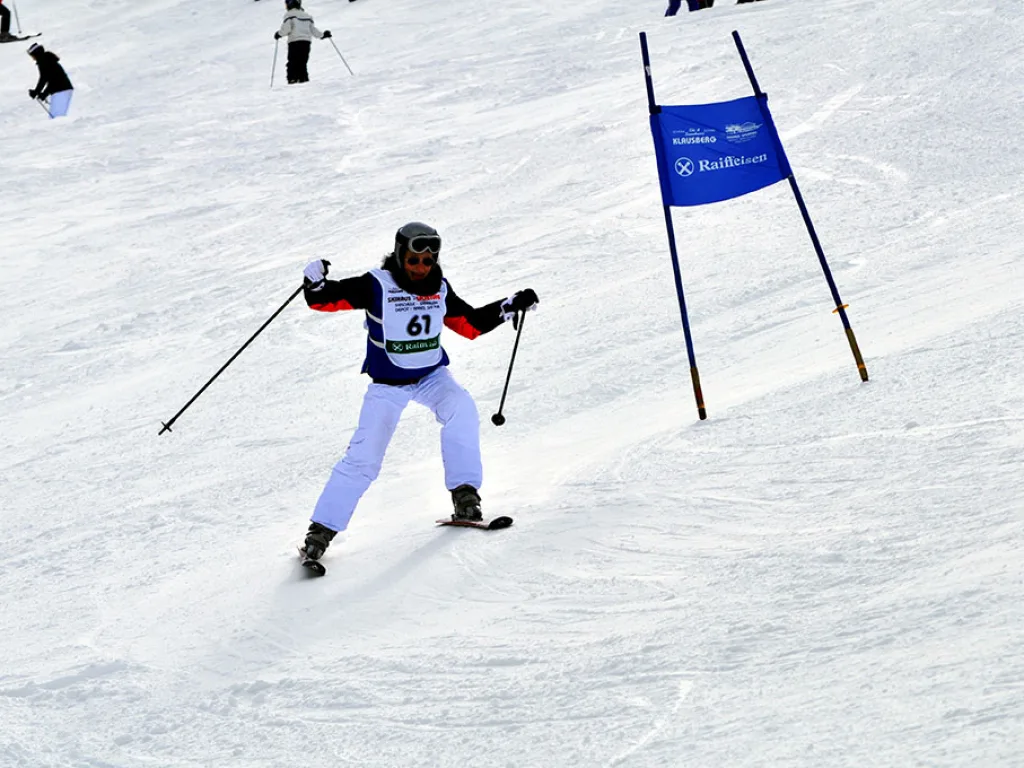 Skifahrerin mit Startnummer 61 in weißer Hose auf der Strecke.